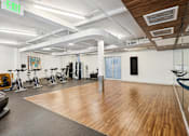 Thumbnail 18 of 31 - A gym with a variety of exercise equipment including treadmills, stationary bikes, and weights.