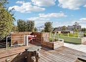 Thumbnail 9 of 31 - A wooden deck with a table and chairs overlooking a cityscape.