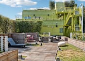 Thumbnail 5 of 31 - A green building with a yellow staircase and a wooden deck in front.