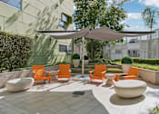 Thumbnail 10 of 31 - A patio with orange chairs and a white umbrella.