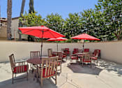 Thumbnail 36 of 54 - A patio with red umbrellas and chairs.