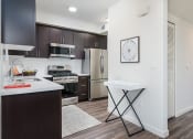 Thumbnail 14 of 25 - a kitchen with dark cabinets and stainless steel appliances