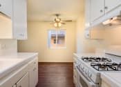 Thumbnail 10 of 16 - A kitchen with a white stove and cabinets.