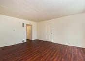 Thumbnail 14 of 16 - A living room with wooden floors and white walls.