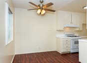Thumbnail 11 of 16 - A kitchen with a wood floor and white walls.