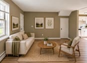 Thumbnail 4 of 14 - A living room with a couch, chair, and pictures on the wall.