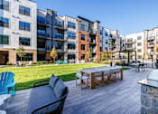 Thumbnail 36 of 61 - A patio with a table and chairs is surrounded by apartment buildings.