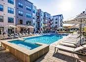 Thumbnail 31 of 61 - A swimming pool surrounded by sun loungers and umbrellas in front of apartment buildings.