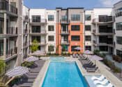 Thumbnail 57 of 61 - an outdoor pool with lounge chairs and umbrellas in front of an apartment building