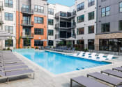 Thumbnail 30 of 61 - a swimming pool with lounge chairs in front of an apartment building