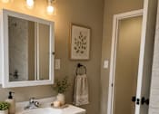 Thumbnail 8 of 14 - A bathroom with a white sink and a mirror above it.