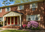 Thumbnail 10 of 14 - A red brick house with a white front door and windows.