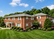 Thumbnail 9 of 14 - A large red brick house with a white door and windows.