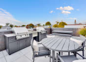 Thumbnail 23 of 35 - an outdoor patio with stainless steel appliances and a table and chairs