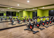 Thumbnail 15 of 53 - Indoor cycling studio with bikes and green accent wall at Inwood at Renaissance Square Apartments, New Jersey