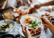 Thumbnail 70 of 80 - a group of people sitting around a table eating food with