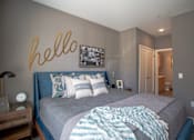 Thumbnail 38 of 53 - Bedroom with blue upholstered bed and ensuite bathroom at Inwood at Renaissance Square Apartments, New Jersey, 08053