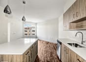 Thumbnail 28 of 53 - Galley kitchen with island and white countertops at Inwood at Renaissance Square Apartments, Marlton, NJ