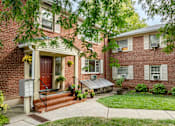 Thumbnail 1 of 5 - A red door is on the left side of a brick house.