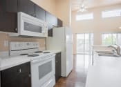 Thumbnail 3 of 18 - a kitchen with white appliances and black cabinets and a white refrigerator