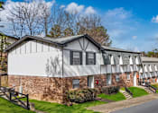 Thumbnail 20 of 22 - A white building with a grey roof is surrounded by greenery.