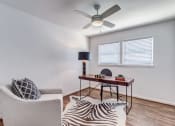 Thumbnail 6 of 18 - a living room with a couch and a desk with a ceiling fan