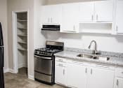 Thumbnail 3 of 12 - A kitchen with white cabinets and a black stove top oven.