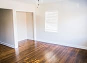 Thumbnail 7 of 12 - A room with wooden floors and a window with blinds.