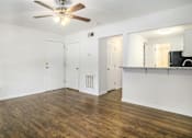 Thumbnail 2 of 12 - A room with a ceiling fan and wooden floors.