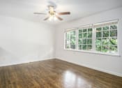 Thumbnail 6 of 12 - A room with a ceiling fan and a window with a view of trees.