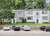 Thumbnail 10 of 12 - A grey building with a black door and a green lawn in front.