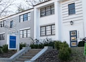 Thumbnail 9 of 12 - A white building with a blue door and windows.