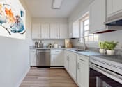 Thumbnail 4 of 22 - A modern kitchen with white cabinets and a large painting on the wall.