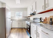 Thumbnail 1 of 22 - A kitchen with a refrigerator, oven, and cabinets.