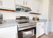 Thumbnail 3 of 22 - A kitchen with white cabinets and a granite countertop.