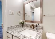 Thumbnail 17 of 22 - A bathroom with a granite countertop and a white sink.