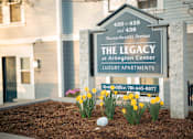 Thumbnail 1 of 28 - A sign for The Legacy at Arlington Center Luxury Apartments is displayed in front of a building.