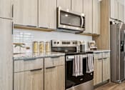 Thumbnail 31 of 46 - A modern kitchen with wooden cabinets and stainless steel appliances.at The Liliana Apartment Homes, Pooler, GA 31322