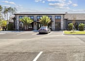 Thumbnail 15 of 46 - A car is parked in a parking lot in front of a building.at The Liliana Apartment Homes, Pooler