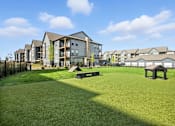 Thumbnail 53 of 59 - A grassy area in front of apartment buildings at The Garrison Luxury Apartment Homes, Fountain, CO 80817