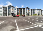 Thumbnail 46 of 46 - A parking lot in front of a multi-story apartment building.at The Liliana Apartment Homes, Pooler Georgia