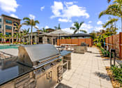 Thumbnail 65 of 65 - A modern outdoor kitchen with a grill and a pool in the background.