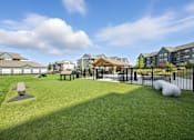 Thumbnail 51 of 59 - A park with a grassy area, picnic tables, and a playground at The Garrison Luxury Apartment Homes, Fountain, CO 80817