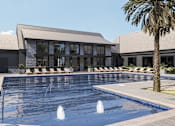 Thumbnail 1 of 11 - A large swimming pool in front of a building with a palm tree to the side at The Pullman Luxury Apartment Homes, Atlanta, GA