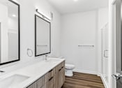 Thumbnail 58 of 124 - Modern bathroom with double vanity and wood flooring at Velara Luxury Apartments, Ponte Vedra Beach, FL