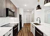 Thumbnail 71 of 105 - A modern kitchen with dark wood cabinets and white countertops. at The Pullman Luxury Apartments, Atlanta, 30349