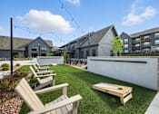 Thumbnail 37 of 59 - A sunny day at a park with wooden benches and a shuffleboard table at The Garrison Luxury Apartment Homes, Fountain, CO 80817