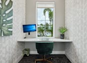 Thumbnail 25 of 62 - A white desk with a green chair and a blue monitor in front of a window.