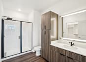 Thumbnail 74 of 105 - A modern bathroom with a walk-in shower, wooden cabinet, and a white sink. at The Pullman Luxury Apartments, Atlanta, Georgia