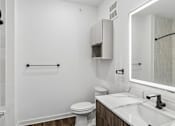Thumbnail 73 of 124 - Modern bathroom with floating vanity and backlit mirror at Velara Luxury Apartments, Ponte Vedra Beach, FL